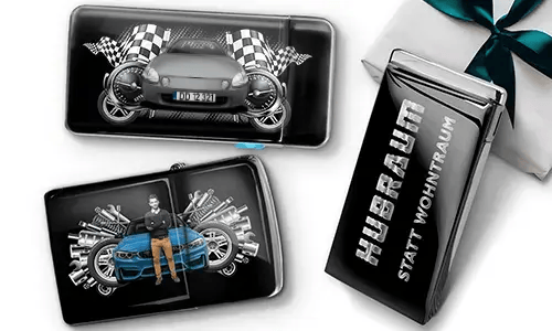 Geschenkset mit Auto-Themen-Metallbehältern, die Bilder eines grünen Sportwagens, karierten Flaggen und Motor-Motiven zeigen. Enthält ein Zigarettenetui mit der Aufschrift „Hubraum Statt Wohntraum“.