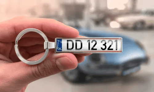 Llavero plateado de placa de matrícula muestra números personalizados mientras se sostiene en la mano