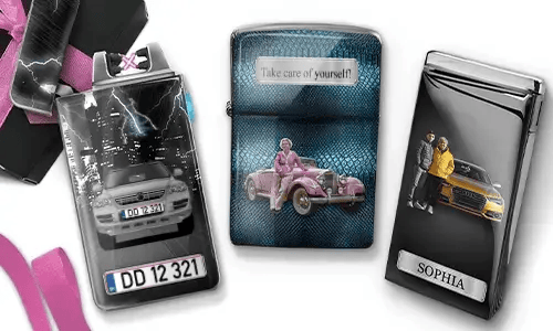 Three metal lighters featuring personalized designs. The left lighter shows a city skyline and a couple beside a car with 'BESTE OMA DER WELT'. The middle lighter depicts a pink vintage car with 'HAB DICH LIEB OMA' above. The right lighter displays a blue car and a license plate. Pink ribbons add a gift-like context.