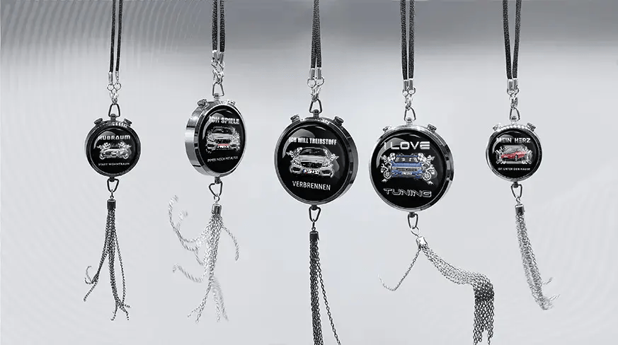 Five round keychains with German car-themed slogans and illustrations, hanging in a row